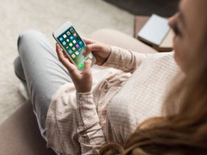 Over-the-shoulder view of a woman using a smartphone with social media apps on the screen, symbolizing digital engagement and online connectivity.