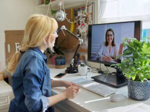 Woman talking to a coach over a virtual video chat on her computer, representing online mentorship and coaching sessions.